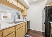 Thumbnail 20 of 41 - A kitchen with wooden cabinets and a black refrigerator. at University Park Apartments, Orlando, Florida