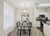Thumbnail 6 of 32 - A dining room with a table set for two and a kitchen in the background. at Cedar Springs Apartments, Raleigh, NC, 27609