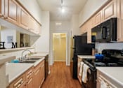 Thumbnail 7 of 45 - A kitchen with wooden cabinets and black appliances. at Heritage at Stone Mountain, Colorado, 80233