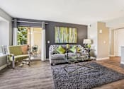 Thumbnail 1 of 41 - A living room with a grey couch and a glass coffee table.