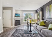 Thumbnail 5 of 41 - A living room with a grey couch and a fireplace.