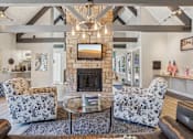 Thumbnail 27 of 44 - A living room with a stone fireplace and a chandelier. at Windmill Apartments, Colorado Springs