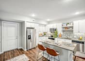 Thumbnail 2 of 86 - a kitchen with stainless steel appliances and a island with three chairs at Edge75, Naples, Florida 34104