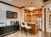 Thumbnail 17 of 45 - a kitchen with a bar and a refrigerator and a tv at Heritage at Stone Mountain, Northglenn, CO, 80233