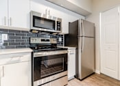 Thumbnail 45 of 117 - a kitchen with white cabinets and stainless steel appliances at Heritage Bay, Jensen Beach, FL