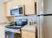 Thumbnail 12 of 117 - a kitchen with wooden cabinets and stainless steel appliances at Heritage Bay, Jensen Beach, 34957