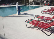 Thumbnail 18 of 24 - Row of red  chairs next to a swimming pool at River Crossing Apartments, Thunderbolt, GA, 31404
