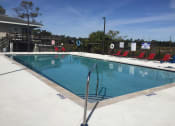 Thumbnail 15 of 24 - Swimming pool with red chairs around iit at River Crossing Apartments, Thunderbolt, GA, 31404