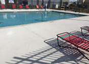 Thumbnail 19 of 24 - Swimming pool with a red chairs next to it at River Crossing Apartments, Thunderbolt, GA, 31404