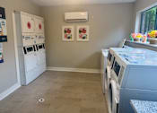 Thumbnail 47 of 51 - A laundry room with a washer and dryer, a refrigerator, and a wall with two framed pictures.