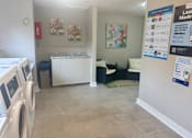 Thumbnail 49 of 51 - A laundry room with a washer and dryer, a bench, and a bulletin board.