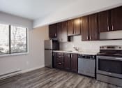 Thumbnail 5 of 50 - Empty kitchen with wooden cabinets and stainless steel appliances and a window  at Governor's Park, Fort Collins, 80525