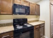Thumbnail 5 of 31 - Kitchen with brown cabinets and black appliances at Arcadia Townhomes, Federal Way, WA