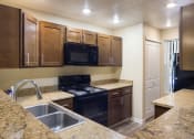 Thumbnail 7 of 31 - A kitchen with wooden cabinets and granite style countertops at Arcadia Townhomes, Federal Way, WA