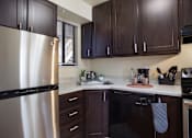 Thumbnail 11 of 50 - Kitchen with stainless steel appliances and dark wood cabinets  at Governor's Park, Fort Collins, 80525