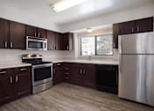 Thumbnail 9 of 50 - Kitchen with dark wood cabinets and stainless steel appliances  at Governor's Park, Fort Collins, 80525