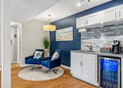 Thumbnail 34 of 64 - Clubhouse area with two blue chairs and a kitchen with a sink at Lofts of Wilmington Apartments, Wilmington, NC