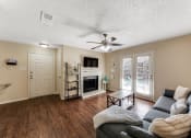Thumbnail 2 of 16 - a living room with a couch and a ceiling fan and a fireplace at The Glen Apartments, Texas