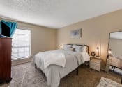 Thumbnail 4 of 16 - a bedroom with a bed and a dresser and a mirror at The Glen Apartments, Texas, 75067