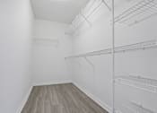 Thumbnail 18 of 50 - an empty room with white walls and wood flooring and a white closet with shelves at Pembroke Pines Landings, Pembroke Pines, Florida