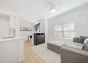 Thumbnail 5 of 65 - A modern living room with a grey couch and a white kitchen area.