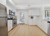 Thumbnail 2 of 65 - A kitchen with white cabinets and a wooden floor.