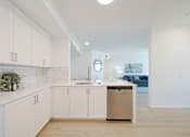 Thumbnail 3 of 65 - A kitchen with white cabinets and a trash can.