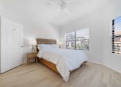 Thumbnail 8 of 65 - A bedroom with a bed, nightstand, and window with blinds.