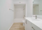 Thumbnail 11 of 65 - A white bathroom with a toilet, sink, and bathtub.