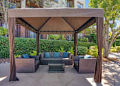 Thumbnail 54 of 65 - A patio with a couch and a table under a canopy.