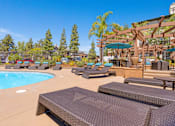 Thumbnail 57 of 65 - A pool area with sun loungers and a shaded seating area.