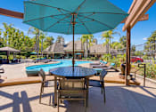 Thumbnail 53 of 65 - A patio with a table and chairs under an umbrella.