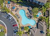 Thumbnail 62 of 65 - An aerial view of a swimming pool surrounded by trees and buildings.