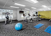 Thumbnail 24 of 27 - an apartment gym with a yoga ball, yoga mats, tv, stationary bikes, and treadmills