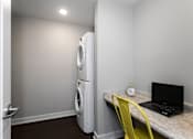 Thumbnail 16 of 27 - a stacked washer and dryer with a pocket desk nearby