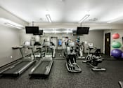 Thumbnail 14 of 22 - A gym with treadmills, exercise bikes, and a mirror.