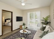 Thumbnail 3 of 22 - A living room with a white couch, a rug, a coffee table, a flat screen TV, and a plant.