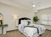Thumbnail 6 of 22 - A bedroom with a bed, a ceiling fan, and a plant.