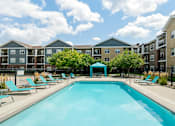 Thumbnail 10 of 22 - A swimming pool surrounded by sun loungers and apartment buildings.