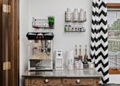 Thumbnail 9 of 24 - A small kitchen with a counter and a coffee machine.