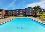Thumbnail 11 of 13 - country club village apartments pool with apartment buildings in the background
