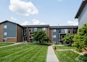 Thumbnail 7 of 24 - Apartment complex with a grassy front yard and a walkway.