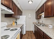 Thumbnail 5 of 24 - A kitchen with brown cabinets and a white stove top oven.