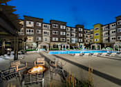 Thumbnail 2 of 27 - an exterior shot of the apartment community with a fireplace and seating and the heated saltwater, resort-style pool