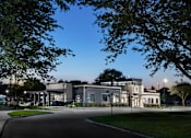 Thumbnail 27 of 37 - modern clubhouse at sunset with large windows and navy siding