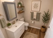 Thumbnail 4 of 17 - A bathroom with a white sink and toilet, a mirror, and a rug on the floor.