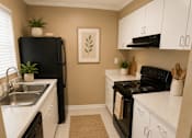 Thumbnail 14 of 14 - A kitchen with black appliances and white cabinets.