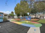 Thumbnail 25 of 29 - a playground with a multicolored circle in the middle of it and some trees at The Groves at Wimauma Apartments , Wimauma