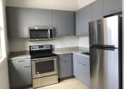 Thumbnail 13 of 18 - a kitchen with gray cabinets and stainless steel appliances at Colonial Apartments, Florida