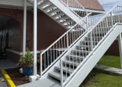 Thumbnail 2 of 18 - a white staircase on the side of a building with a cloudy sky in the background at Colonial Apartments, Orlando, FL